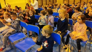 dzieci siedzą i oglądają koncert
