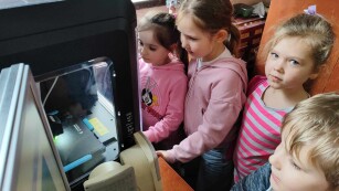 dzieci obserwują wydruk 3D drukarki