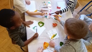 Dzieci  tworzą paprykowe stempelki z użyciem farb i przekrojonych warzyw