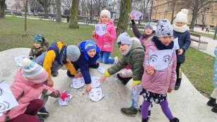 dzieci układają paierowe twarze na kamieniu