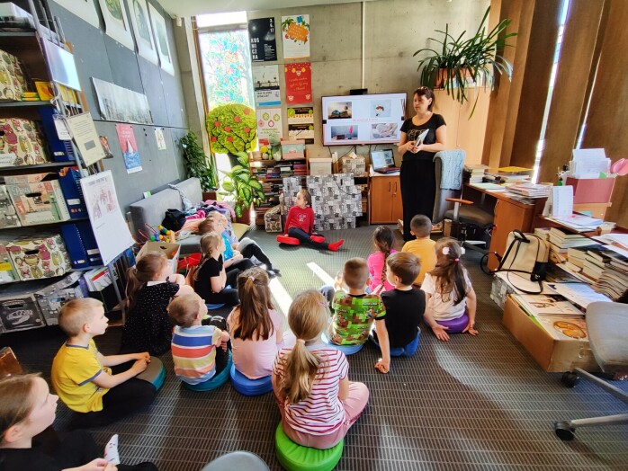 Bibliotekarka prowadzi lekcję, dzieci siedzą i słuchają